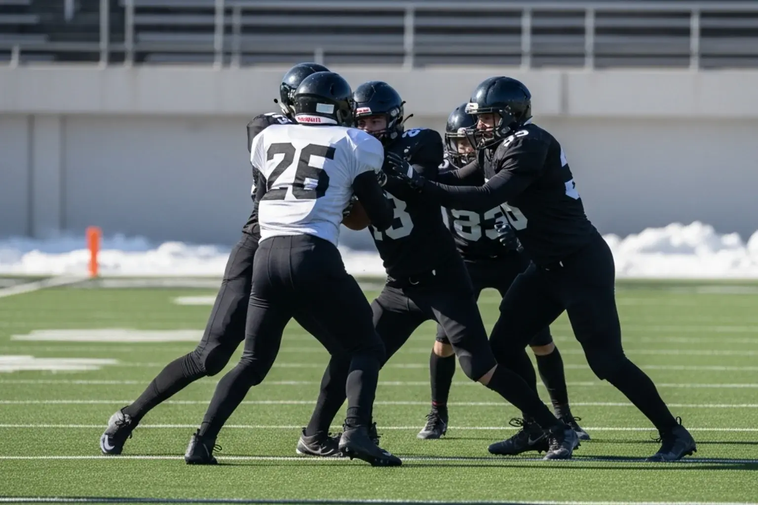 American football players in generic uniforms engaged on a winter stadium pitch with light snow